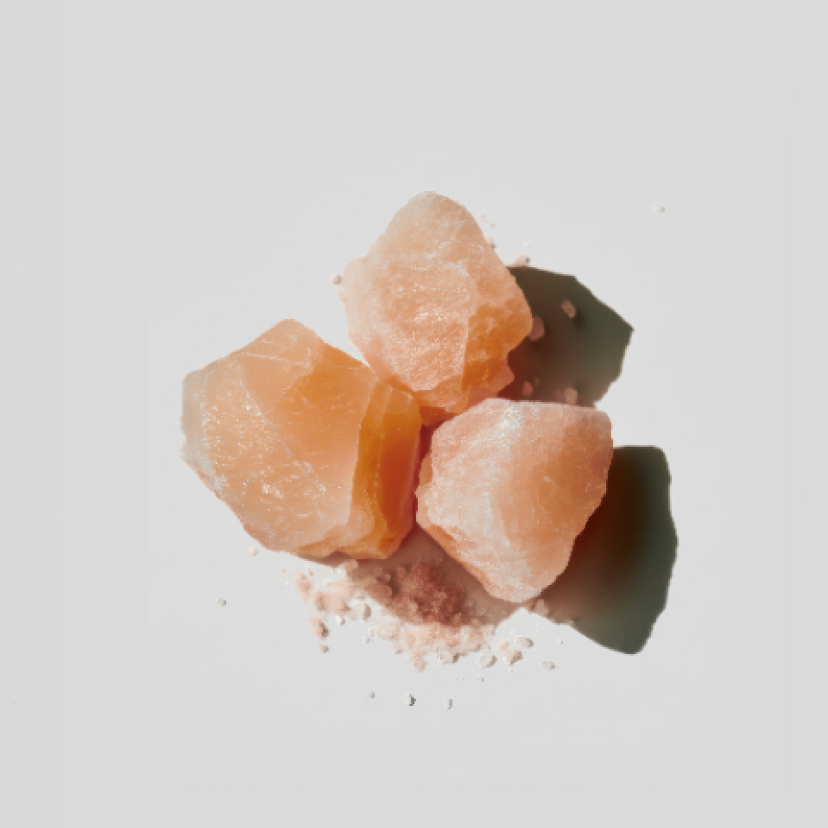 Pink Himalayan salt crystals on a light gray background